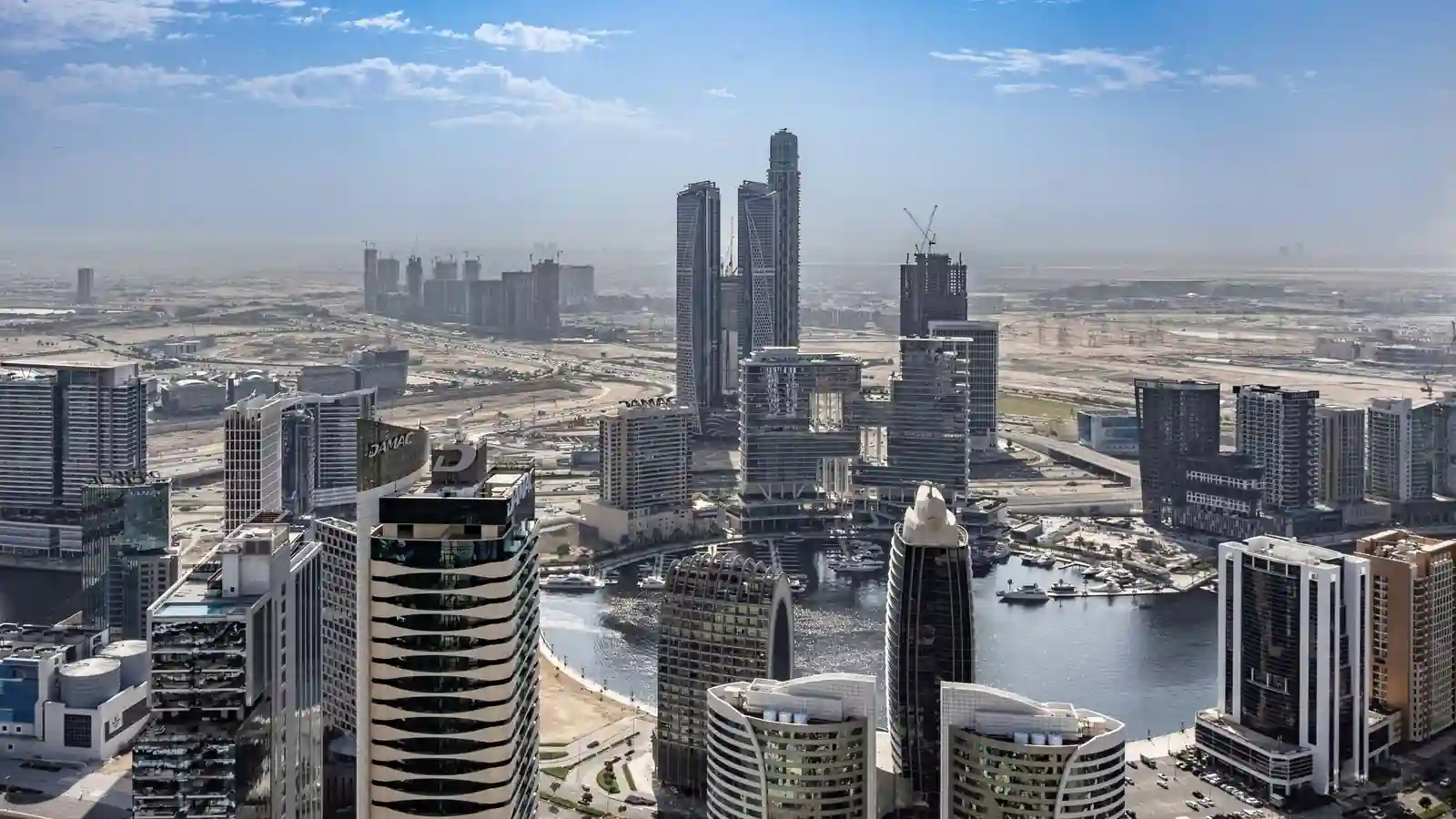 Aerial daytime view of Business Bay's canal basin and marina surrounded by high-rise towers