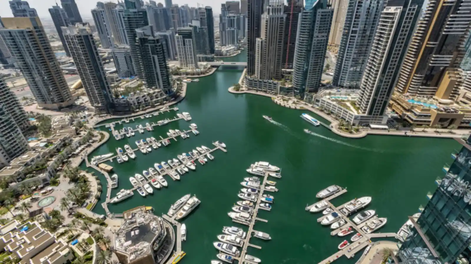 Aerial daytime view of Dubai Marina's yacht-lined waterway framed by waterfront towers