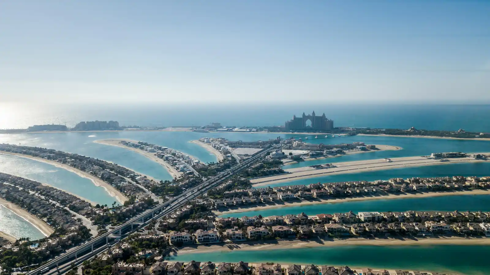 Aerial daytime view of Palm Jumeirah's fronds and villas with Atlantis The Palm on the horizon