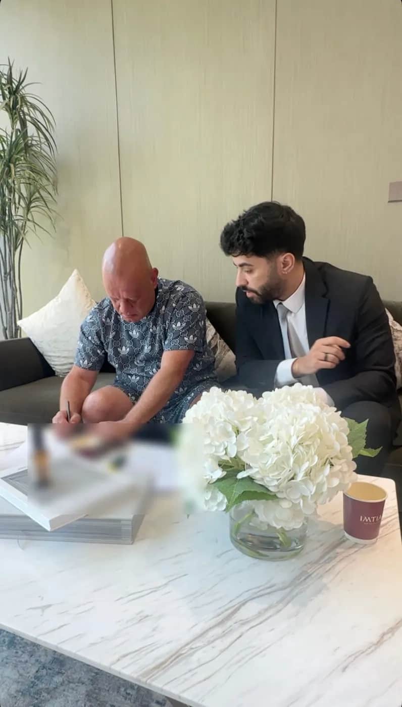 A client signing purchase paperwork with a developer representative in Dubai