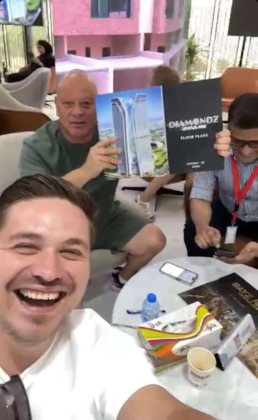 A client holding a project floor-plan brochure in a developer sales lounge: Diamondz by Danube